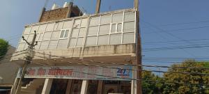 a tall white building with a sign in front of it at Hotel V L in Lucknow