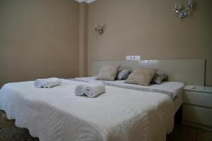 Un dormitorio con una gran cama blanca con toallas. en Apartamento Parque 2 Playa de Gandía, en Playa de Gandía 56 fotos más