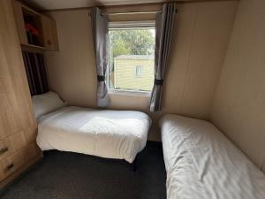 two beds in a small room with a window at Sunningdale comfy suite in Tattershall