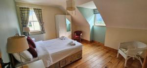 a bedroom with a bed and two windows at Charming Coastal Cottages by Portsalon Beach in Portsalon