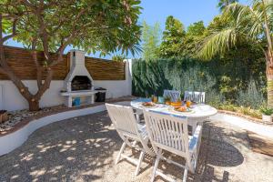 eine Terrasse mit einem Tisch, Stühlen und einem Grill in der Unterkunft TIKI 4 - Casa playamar a 5 min de la playa in Torremolinos