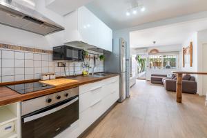 eine Küche mit weißen Geräten und ein Wohnzimmer in der Unterkunft TIKI 4 - Casa playamar a 5 min de la playa in Torremolinos