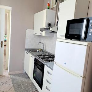 a white kitchen with a sink and a stove at Casa Dolce Casa in Novi Ligure +2 photos