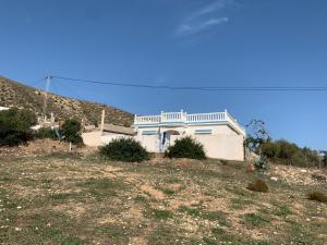 a white house on a hill in a field at Villa Cap Zebib proche mer in Al Matlīn