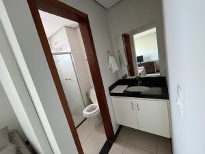 Un baño con inodoro, lavabo y espejo. en Flat paraíso, en Montes Claros 32 fotos más