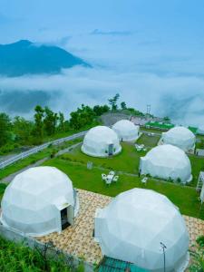 a group of white domes on a field with mountains at Navira Hills Domes Rishikesh in Shivpuri