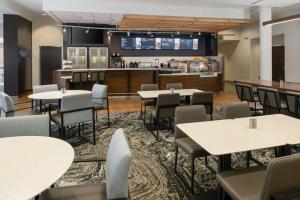 a dining room with tables and chairs and a kitchen at Courtyard by Marriott Houston City Place in Spring