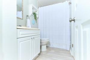 a white bathroom with a toilet and a shower at Summer Breeze D212 - Bungalow 6 in Destin +23 photos