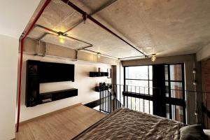 Central Medellin Modern Loft - Balcony and Transit في ميديلين: غرفة نوم بها سرير وتلفزيون على الحائط
