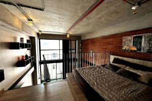 Central Medellin Modern Loft - Balcony and Transit في ميديلين: غرفة نوم بها سرير وجدار من الطوب