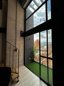 Central Medellin Modern Loft - Balcony and Transit في ميديلين: غرفة مع نافذة كبيرة مع أرضية خضراء