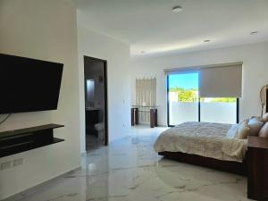 Un dormitorio con una cama y un televisor de pantalla plana. en Privada Huayacan, en Cancún 84 fotos más