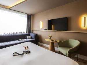 a hotel room with a bed and a couch and a tv at Novotel Nancy in Nancy