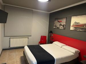 a bedroom with a bed with a red headboard at HOTEL CEAO in Lugo
