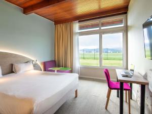 a hotel room with a bed and a desk and a window at Ibis Styles Colmar Nord in Colmar