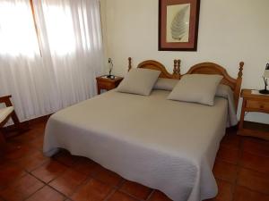 una camera da letto con un grande letto bianco con due cuscini di El Almendro a Tesbabo
