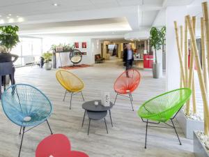 une pièce avec des chaises et des tables dans un hall dans l'établissement Novotel Perpignan Nord Rivesaltes, à Rivesaltes