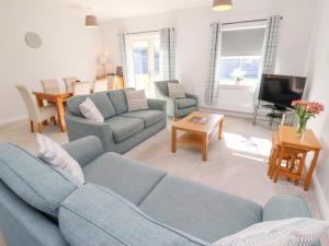 a living room with a blue couch and a tv at The Haven in Alnwick
