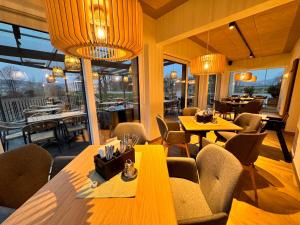 a restaurant with wooden tables and chairs and windows at Groß Genuss in Kaibing
