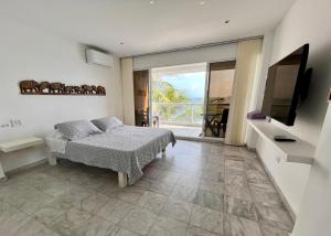a bedroom with a bed and a television and a balcony at Aptos Sunrise Beach in San Andrés