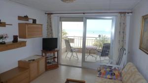 a living room with a television and a balcony at Primera línea Playa Gandia in Gandía