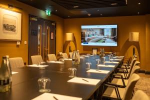 a room with a long table with chairs and a tv at Hotel Indigo Leeds by IHG in Leeds