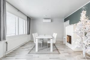 a dining room with a white table and a christmas tree at Santa's choice for Aurora hunters , Sauna and jacuzzi in Rovaniemi