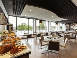 a restaurant with tables and chairs and food on display at Novotel Limoges Le Lac in Limoges
