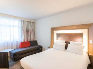ブロンにあるNovotel Lyon Bron Meeting & Eventsのベッドとソファのあるホテルの部屋