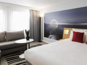 a hotel room with a bed and a couch at Novotel Strasbourg Centre Halles in Strasbourg