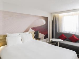 a hotel room with a white bed and a couch at Novotel Strasbourg Centre Halles in Strasbourg