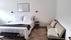 a white bedroom with a bed and a couch at Appartamento vicino a Firenze in Prato