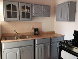 a kitchen with gray cabinets and a sink and a stove at Casa cerca de la playa in Ensenada