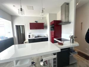 cocina con encimera blanca y armarios rojos en Le tableau, en Pourville-sur-Mer