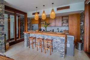 a kitchen with a large stone counter with bar stools at Ocama in Las Galeras +46 photos