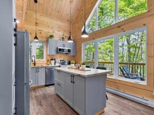 a kitchen with wooden walls and a wooden ceiling at NEW Chalet des pins - lake access in Saint-Alphonse-Rodriguez