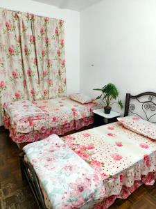 zwei Betten in einem Zimmer mit rosa Blumen in der Unterkunft Dihome Ariel Studio in Donggongon