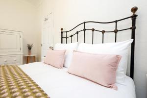 a bedroom with a white bed with pink pillows at Spacious 3 Bedroom Home In The Heart Of Port Talbot By EKLIVING - Short Lets & Serviced Accommodation in Port Talbot