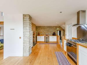 a kitchen with white cabinets and a stone wall at 3 Bed in Coleford 89806 in Coleford +12 photos