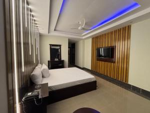 a bedroom with a bed and a tv on a wall at Sapphire Stays Hotel and Restaurant Peshawar in Peshawar