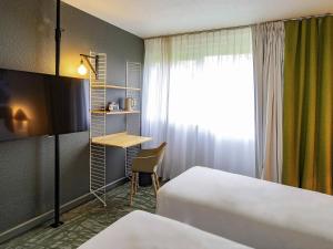 a hotel room with two beds and a desk and a window at Novotel Metz Amnéville in Maizières-lès-Metz +181 photos