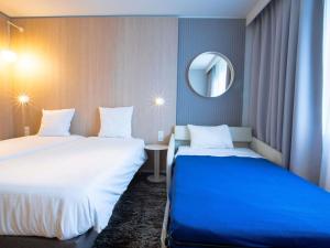 a hotel room with two beds and a mirror at Novotel Mulhouse Bâle Fribourg in Sausheim