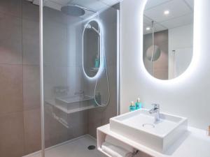 a white bathroom with a sink and a mirror at Novotel Mulhouse Bâle Fribourg in Sausheim +93 photos