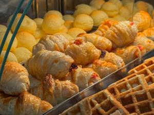 a bunch of croissants and waffles in a bakery at Pousada Vilage Inn Campos do Jordão in Campos do Jordão