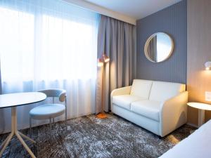 a living room with a white couch and a mirror at Novotel Mulhouse Bâle Fribourg in Sausheim