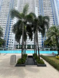 a group of palm trees in front of a building at Skyview 2BR at Grass in Manila