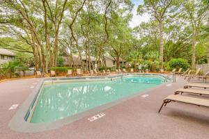 a large swimming pool with chairs and trees at Walk to Folly Field Beach Condo with Pool Access in Hilton Head Island