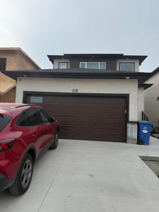 a red car parked in front of a garage at Friendly Extended Stay and Comfort in Winnipeg