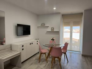 a kitchen with a glass table and pink chairs at Hotel Apartamentos Antequera in Antequera +44 photos