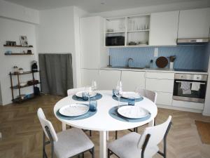 a white kitchen with a white table and chairs at L'Azur - Appartement spacieux - Arrivée Autonome in Brest